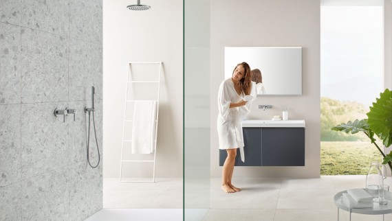 Kobieta susząca włosy ręcznikiem w łazience z otwartą strefą prysznica i dużymi płytkami w stylu lastryko