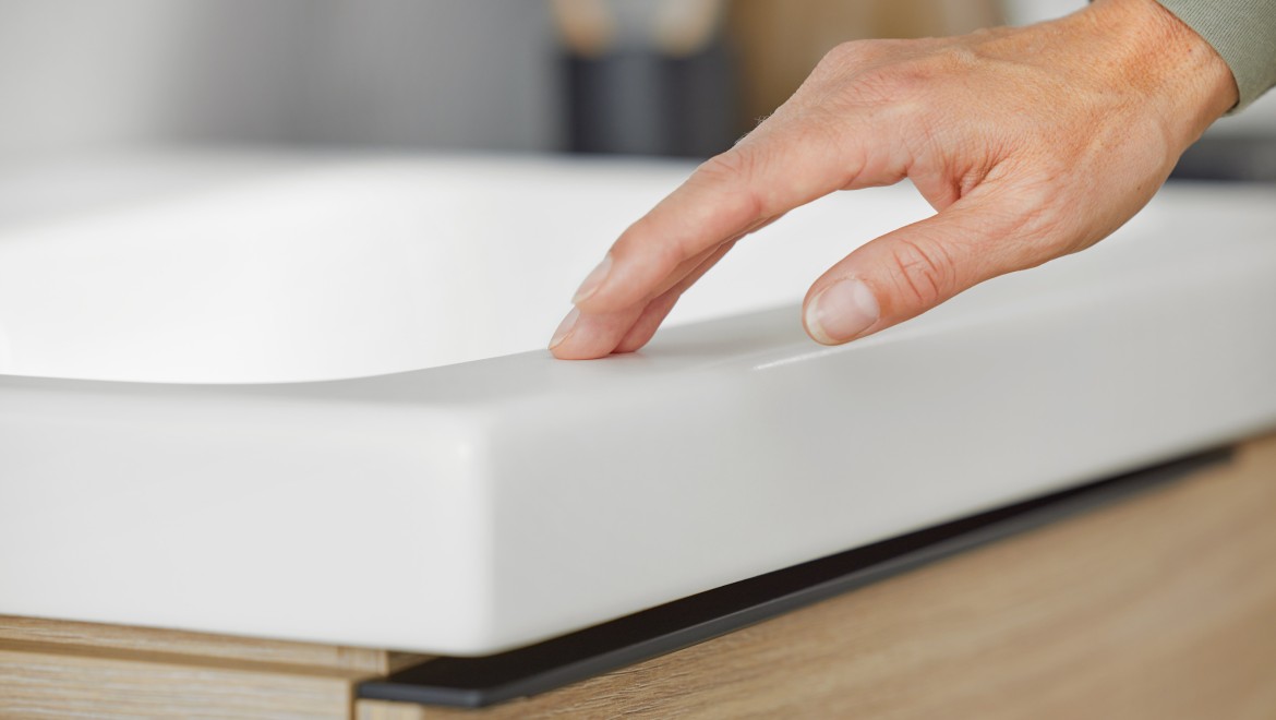 Zdjęcie przedstawiające zbliżenie na dłoń dotykającą umywalkę z serii Geberit iCon w kolorze biały mat