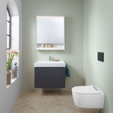 Mała łazienka w kolorze miętowym z szafką pod umywalkę w kolorze lawy, szafką z lustrem, przyciskiem uruchamiającym i ceramiką sanitarną firmy Geberit